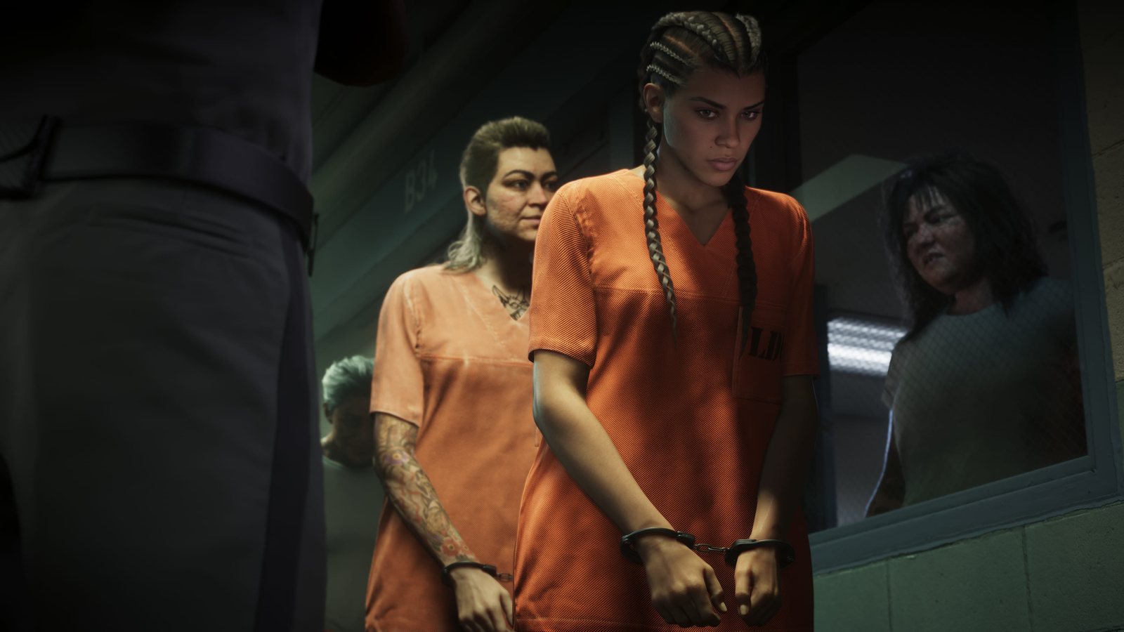 Lucia Caminos in an orange prison uniform, hands cuffed, walks a corridor between two other inmates. Image: Rockstar Games.