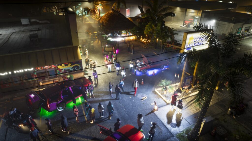 A night street party seen from above: crowds gathered around cars with purple and green underglow outside a Conch King restaurant, palms and overhead wires lit by streetlights. Image: Rockstar Games.